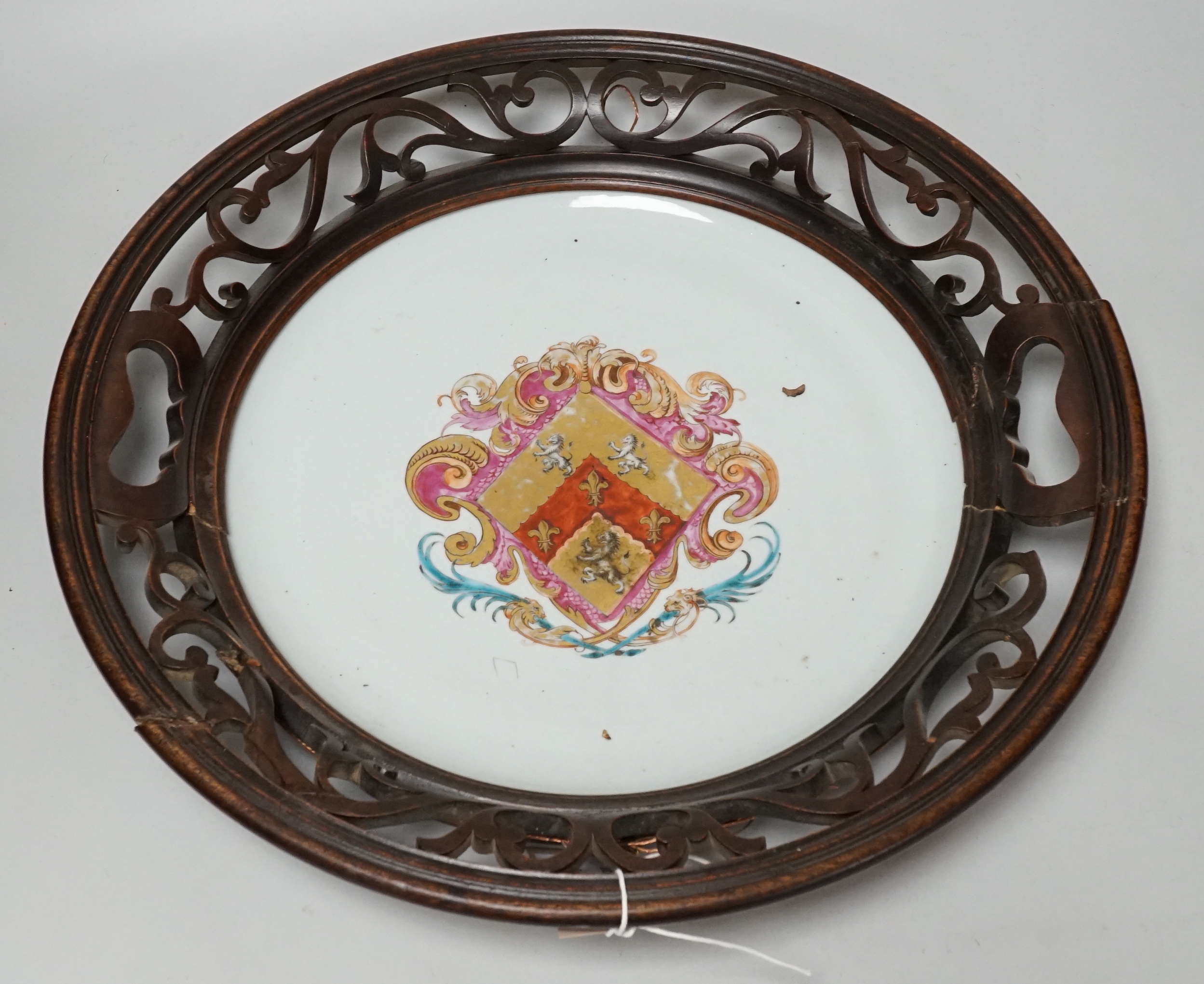 An 18th century Chinese armorial dish, rim cut down and mounted in a 19th century English mahogany frame, 39cm diameter